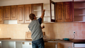 a person installing wooden kitchen cabinets